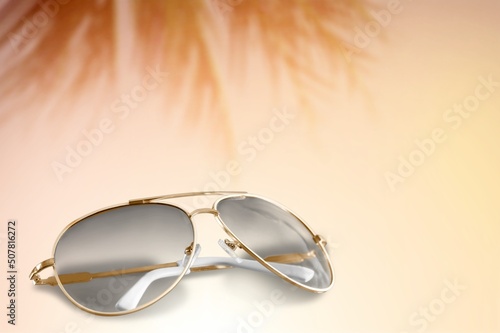 Trendy sunglasses still life in minimal stile. Womens sunglasses on a background with palm leaf, summer fashion concept. Fashionable accessories. Optic store discount, sale.