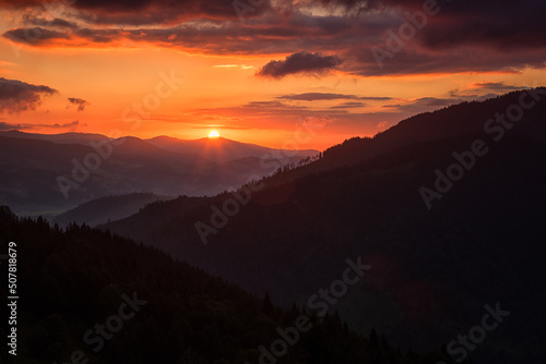 Amazing sunset mountain landscape. Fantastic view of the mountain range, colored sky with clouds and sun, natural outdoor travel background, Carpathian Biosphere Reserve