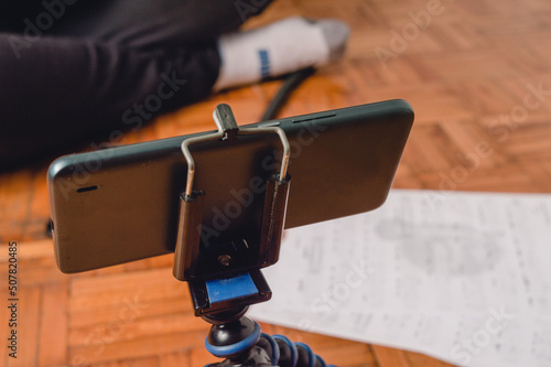 close up phone on a tripod front of an unrecognizable person sitting on the floor photo