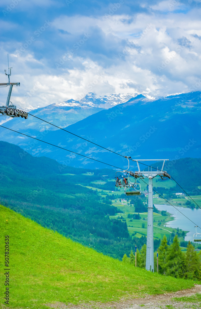 Summer landscape with cable car and bicycles, mountains and lake Weissensee in the distance