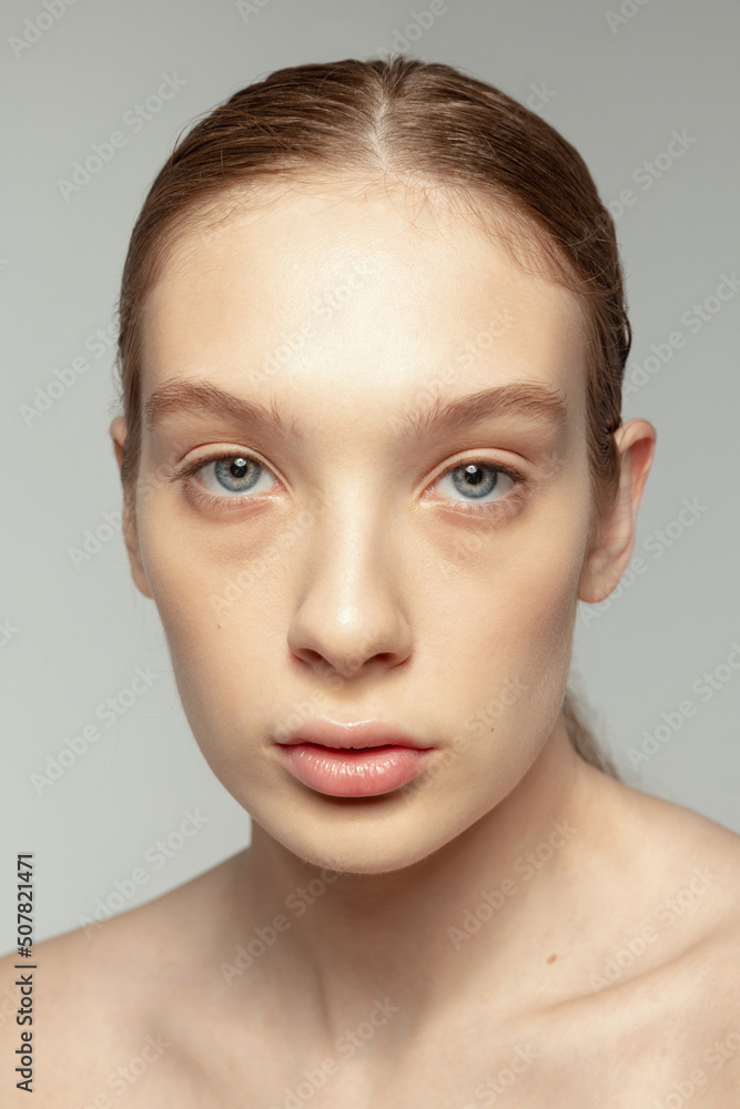Close-up portrait of young beautiful girl with clear smooth skin isolated over grey studio background Close-up portrait of young beautiful girl with clear smooth skin isolated over grey studio background