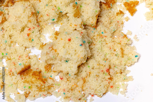 Crumbled confetti birthday cake spread on a white background. photo