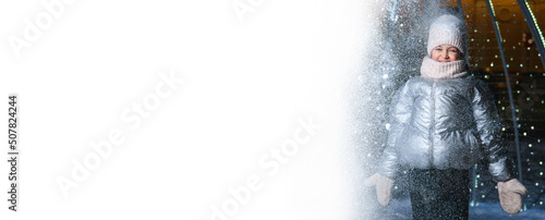 Girl and snow. Smiling girl in warm clothes throws snow outdoors at night with blue backlight on a white isolated background. Banner