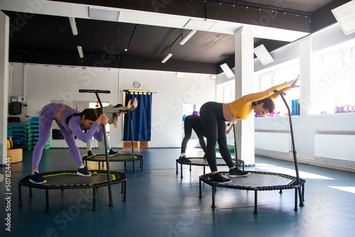 Four young women on trampoline, young fitness girls trains on fitness studio.