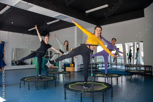 Four young women on trampoline, young fitness girls trains on   fitness studio. photo