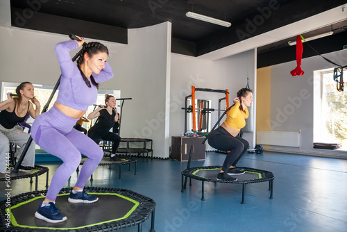 Group of happy women warming up before training in   gym jumping on   trampoline photo