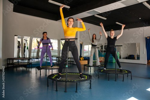 Group of happy women warming up before training in   gym jumping on   trampoline