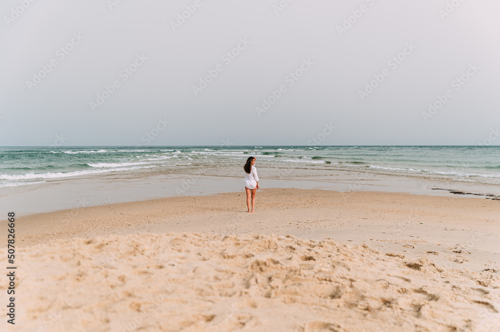 woman in white dress standing on sandy beach