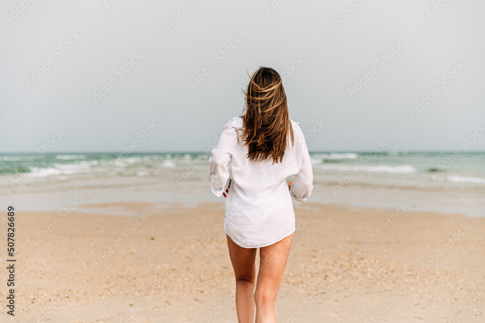 woman in white dress standing on sandy beach woman in white dress standing on sandy beach