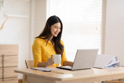 Entrepreneur beautiful business asian young woman wear yellow shirt work online with laptop at home.Freelance female working online sale marketing at home.Small Business Startup concept