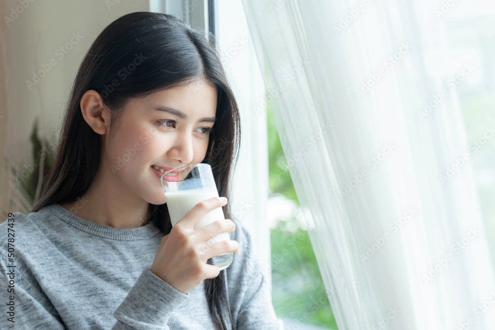 Beautiful beauty Asian woman cute girl feel happy drinking milk for good health in the morning , enjoying time in her home white bedroom background - lifestyle beauty woman concept Beautiful beauty Asian woman cute girl feel happy drinking milk for good health in the morning , enjoying time in her home white bedroom background - lifestyle beauty woman concept