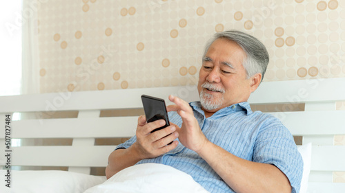 Tela Senior Male using a smartphone , smiling feel happy in bed at home - lifestyle s