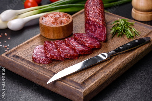 Smoked salami with rosemary, garlic and tomatoes on wooden cutting board