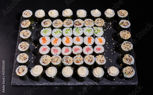 Japanese sushi set. Different types of maki rolls on a plate on a stone background.