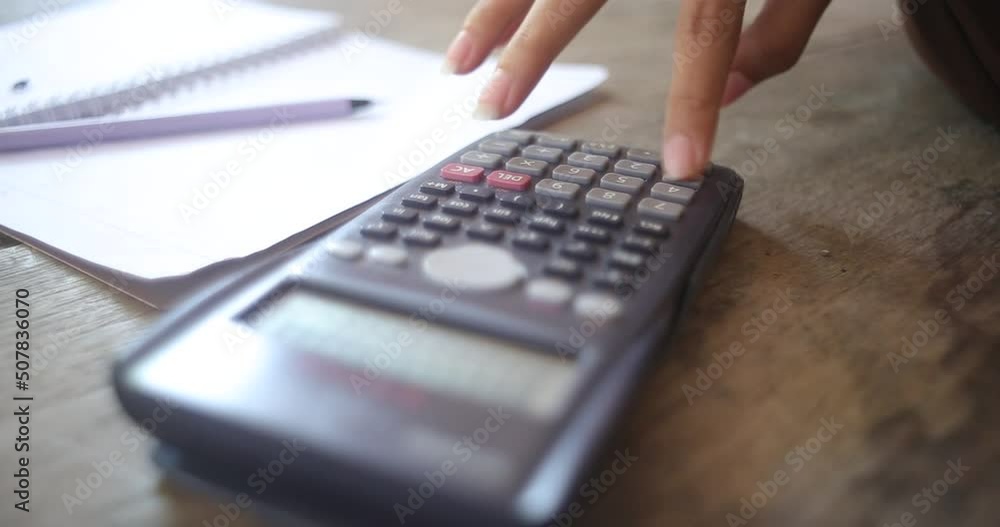Business woman's hands using calculator and Financial data analyzing on wooden desk at the office Business woman's hands using calculator and Financial data analyzing on wooden desk at the office