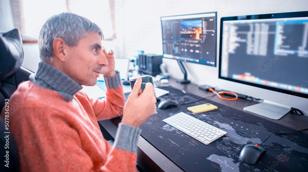 Man works from home in front of computer sipping a cup of tea. Man works from home in front of computer sipping a cup of tea.