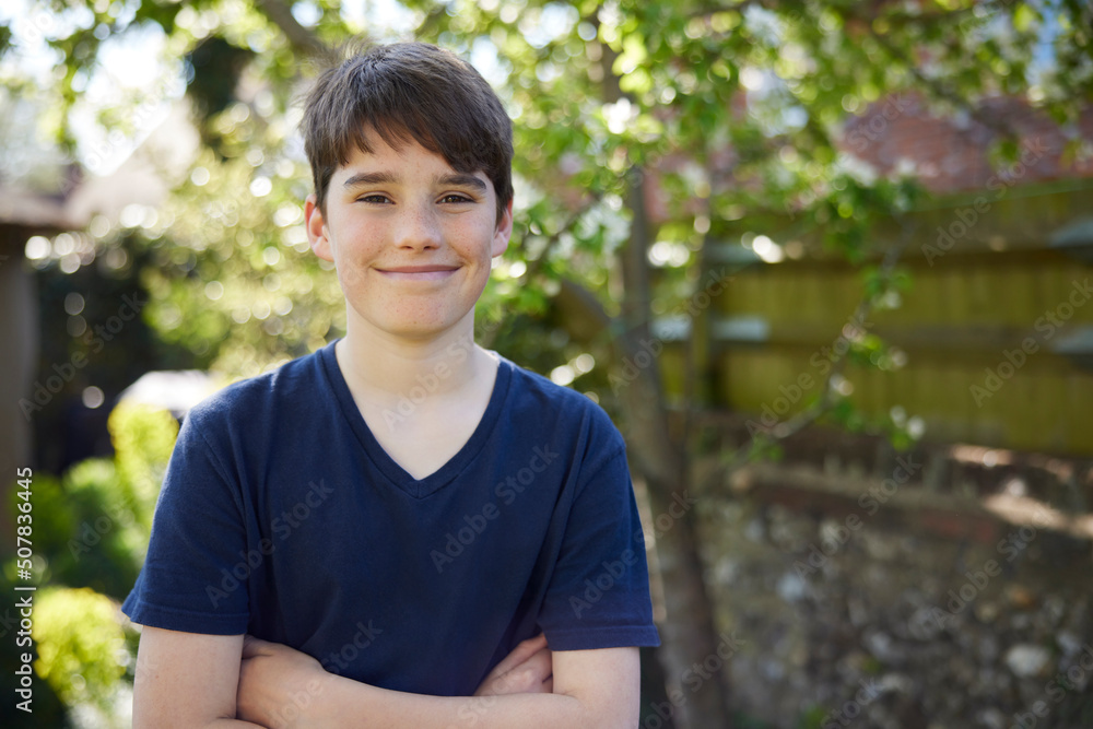 Portrait Of Smiling Teenage Boy With Crossed Arms Standing In Summer Garden At Home Portrait Of Smiling Teenage Boy With Crossed Arms Standing In Summer Garden At Home