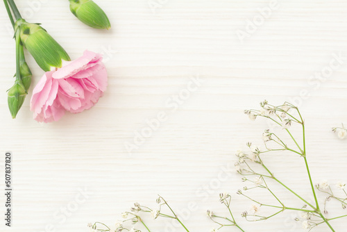 Fototapeta Naklejka Na Ścianę i Meble -  淡い木目のテーブルの上のピンクのカーネーションと白いかすみ草