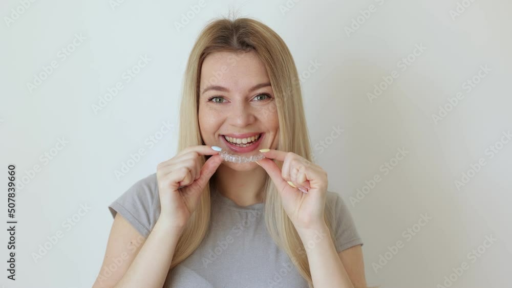 Smiling girl putting transparent aligner in teeth Smiling girl putting transparent aligner in teeth