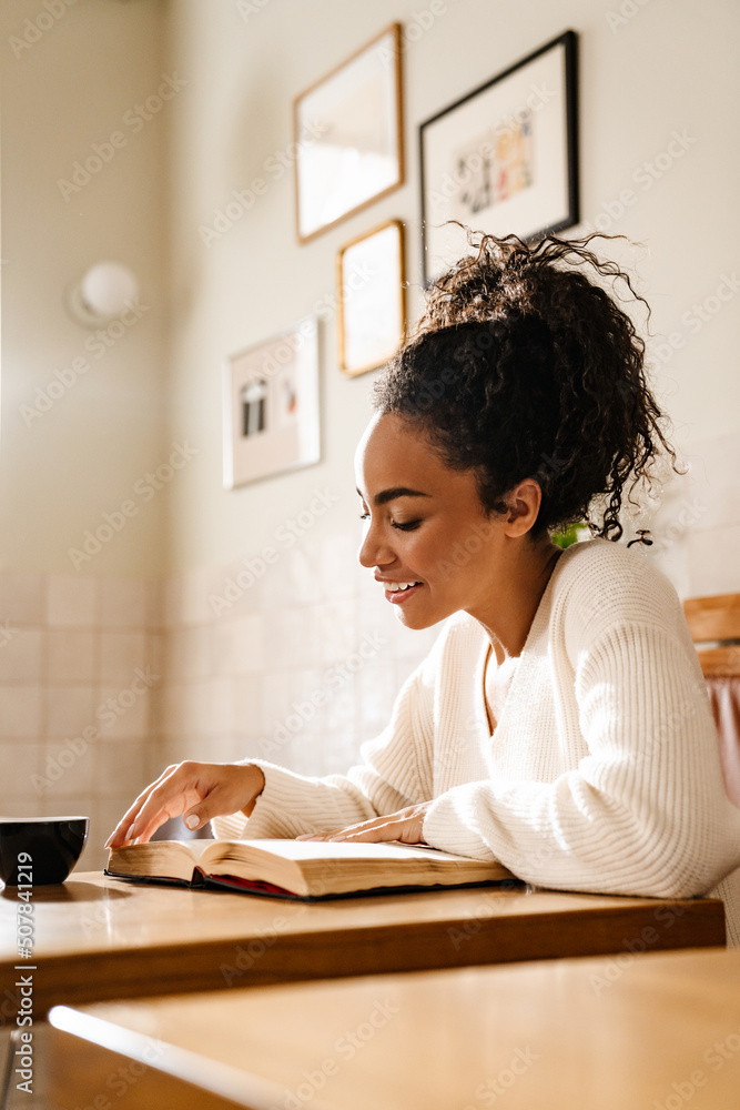 Young black woman smiling and reading book in cafe Young black woman smiling and reading book in cafe
