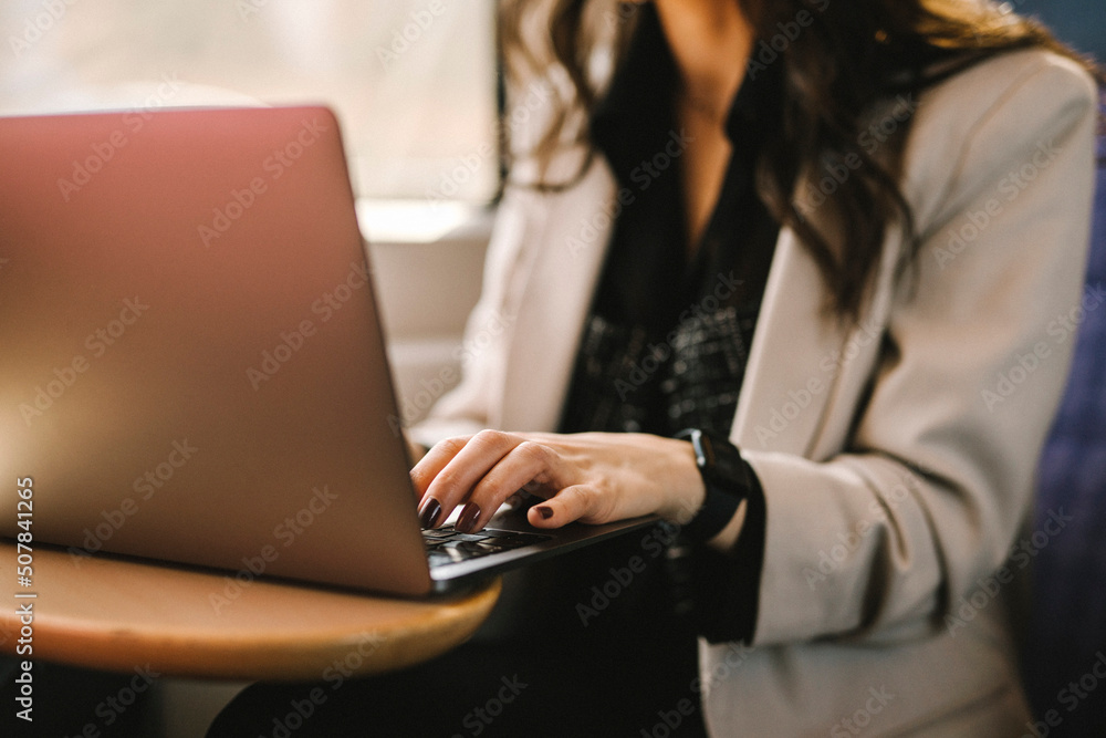Midsection of businesswoman using laptop while commuting in train Midsection of businesswoman using laptop while commuting in train