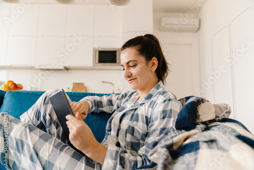 Young woman using tablet computer while resting on couch