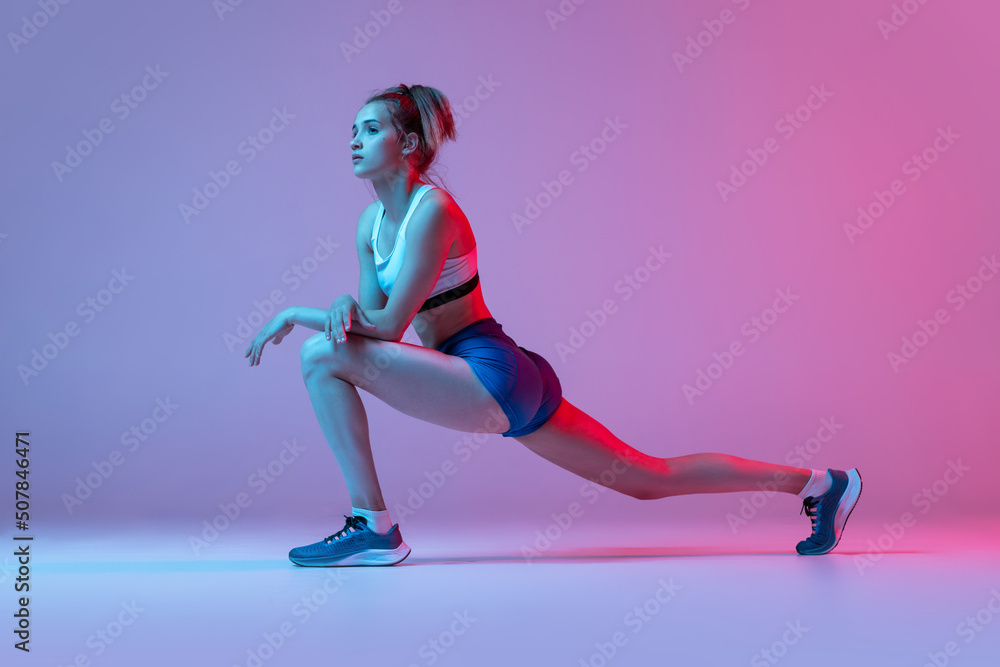 Studio shot of professional female athlete, runner training isolated on pink studio background with blue neon filter, light. Concept of action, motion, speed Studio shot of professional female athlete, runner training isolated on pink studio background with blue neon filter, light. Concept of action, motion, speed