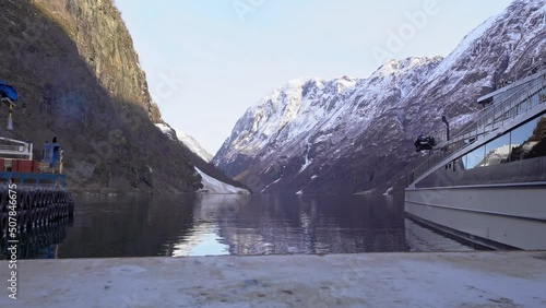 Unesco listed Naeroyfjorden seen from Gudvangen harbor with electric sightseeing boat Vision of the fjords to the right - Slow moving slider from right to left during winter morning - Norway photo