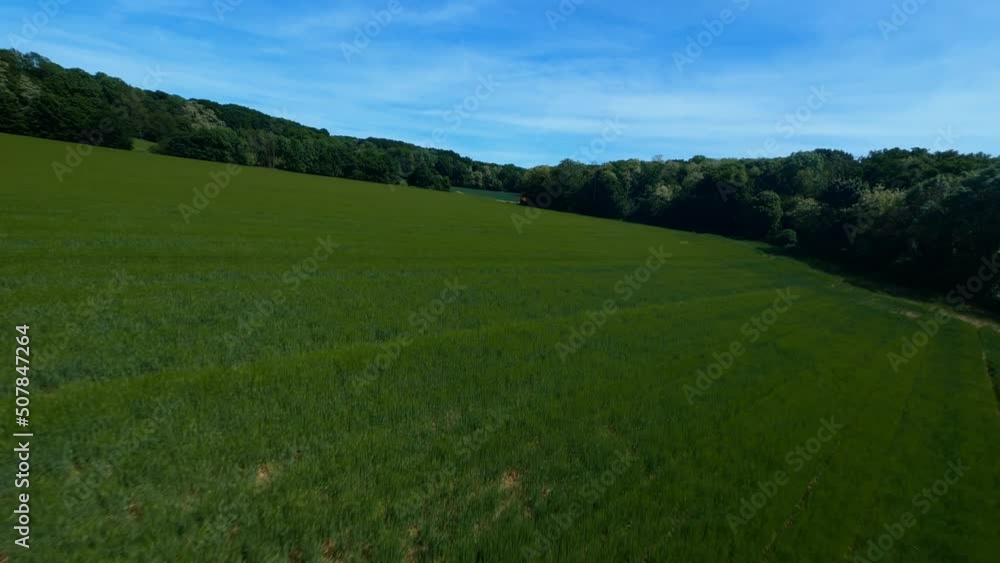 FPV DRONE SHOT - Flight over green field and around a red container FPV DRONE SHOT - Flight over green field and around a red container