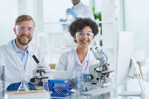 Smiling scientists looking at camera arms crossed in laboratory