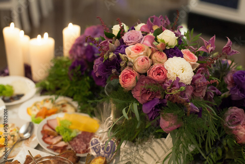Festive served table for the bride and groom, decorated with flowers in vases, at a banquet, in a restaurant.