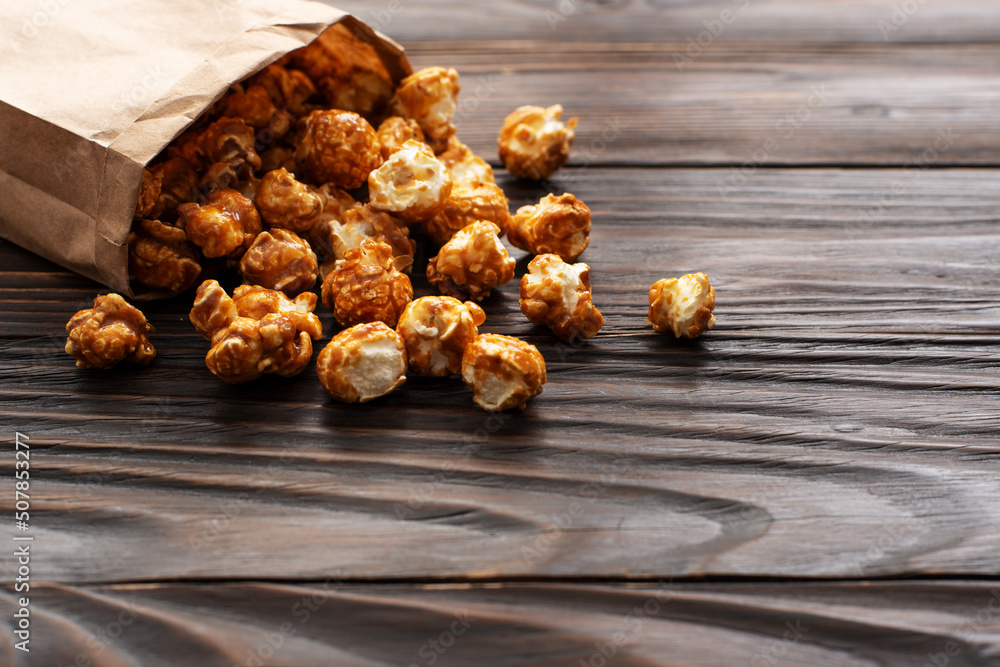 Caramelized popcorn in paper bag on wooden kitchen table