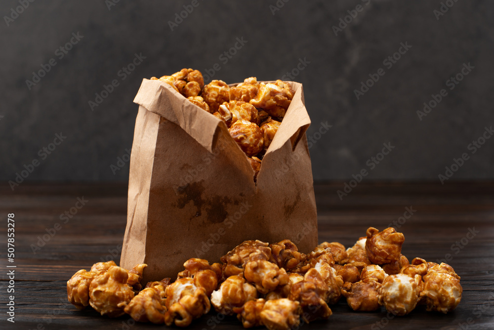 Caramelized popcorn in paper bag on wooden kitchen table
