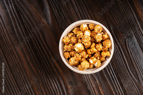 Obraz na płótnie Caramelized popcorn in paper bucket on wooden kitchen table flat lay w salonie