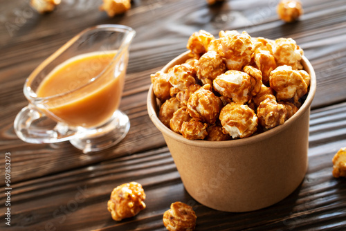 Obraz na płótnie Caramelized popcorn in paper bucket on wooden table w salonie