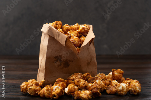 Obraz na płótnie Caramelized popcorn in paper bag on wooden kitchen table w salonie