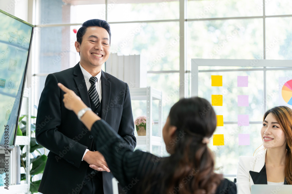 An Asian businessman is presenting his company performance report to his boss or group of male and female colleagues with confidence and professionalism. An Asian businessman is presenting his company performance report to his boss or group of male and female colleagues with confidence and professionalism.