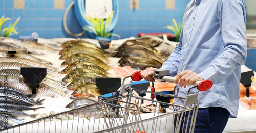 man shopping for fresh fish seafood in supermarket