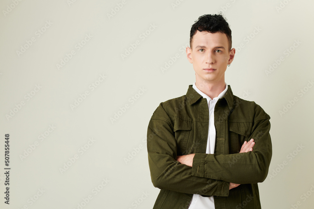 Portrait of confident young man with piercing in left ear crossing arms and looking at camera Portrait of confident young man with piercing in left ear crossing arms and looking at camera