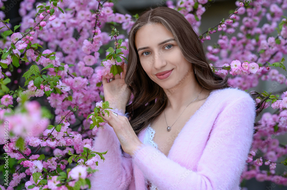Beautiful young woman near blossoming sakura tree on spring day