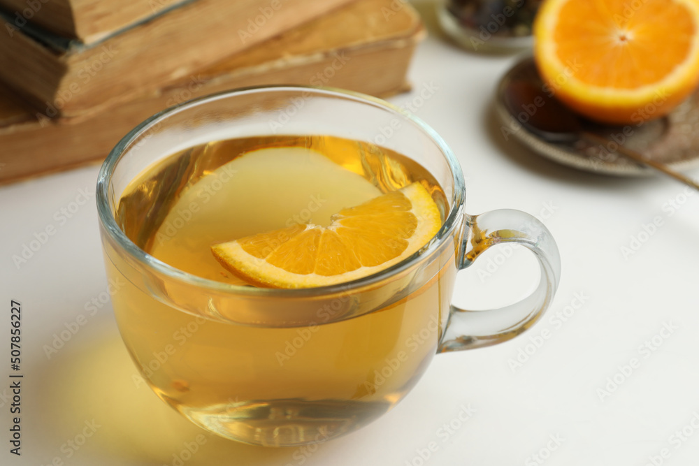 Glass cup of freshly brewed tea with orange on light table, closeup Glass cup of freshly brewed tea with orange on light table, closeup
