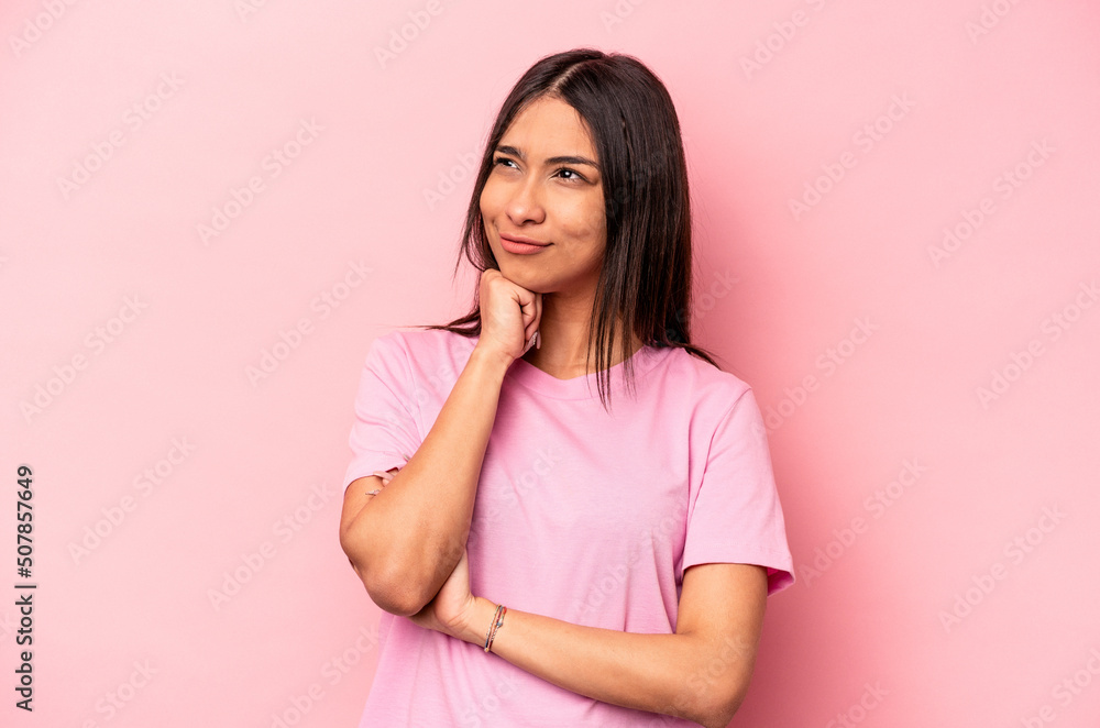 Young hispanic woman isolated on pink background thinking and looking up, being reflective, contemplating, having a fantasy. Young hispanic woman isolated on pink background thinking and looking up, being reflective, contemplating, having a fantasy.