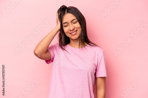 Young hispanic woman isolated on pink background tired and very sleepy keeping hand on head.