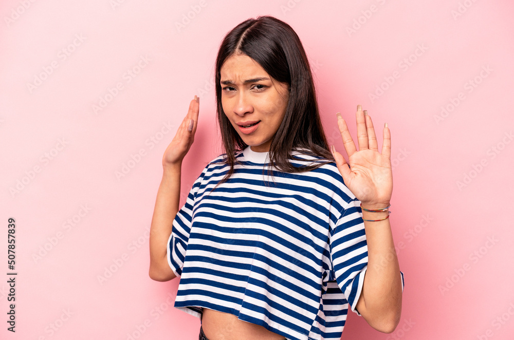 Young hispanic woman isolated on pink background being shocked due to an imminent danger Young hispanic woman isolated on pink background being shocked due to an imminent danger