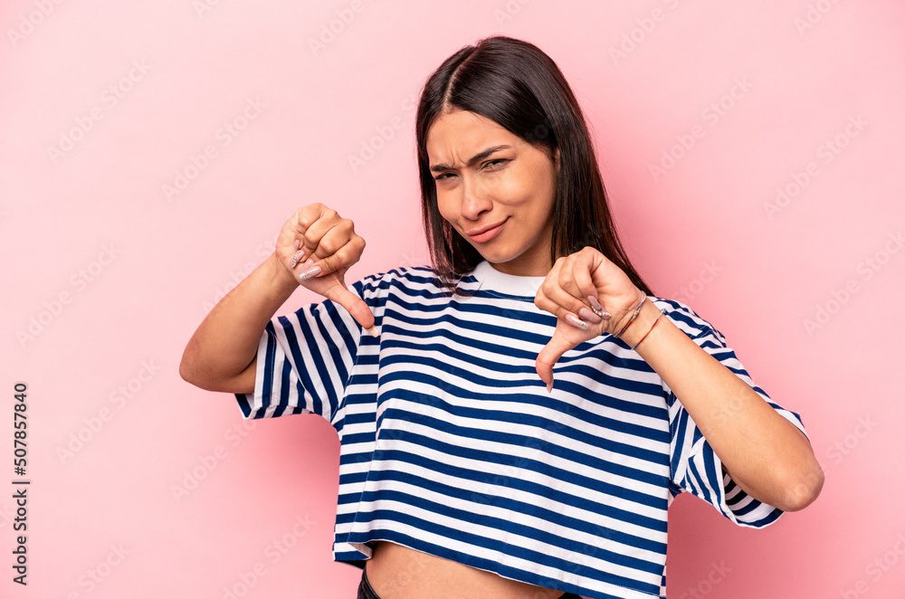 Young hispanic woman isolated on pink background showing thumb down, disappointment concept. Young hispanic woman isolated on pink background showing thumb down, disappointment concept.