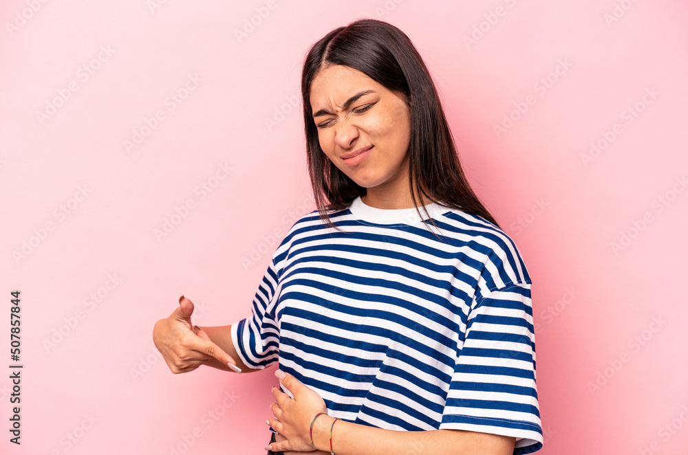 Young hispanic woman isolated on pink background having a liver pain, stomach ache. Young hispanic woman isolated on pink background having a liver pain, stomach ache.