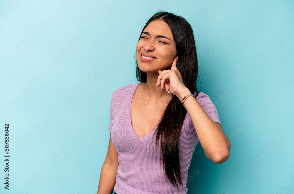 Young hispanic woman isolated on blue background covering ears with fingers, stressed and desperate by a loudly ambient. Young hispanic woman isolated on blue background covering ears with fingers, stressed and desperate by a loudly ambient.