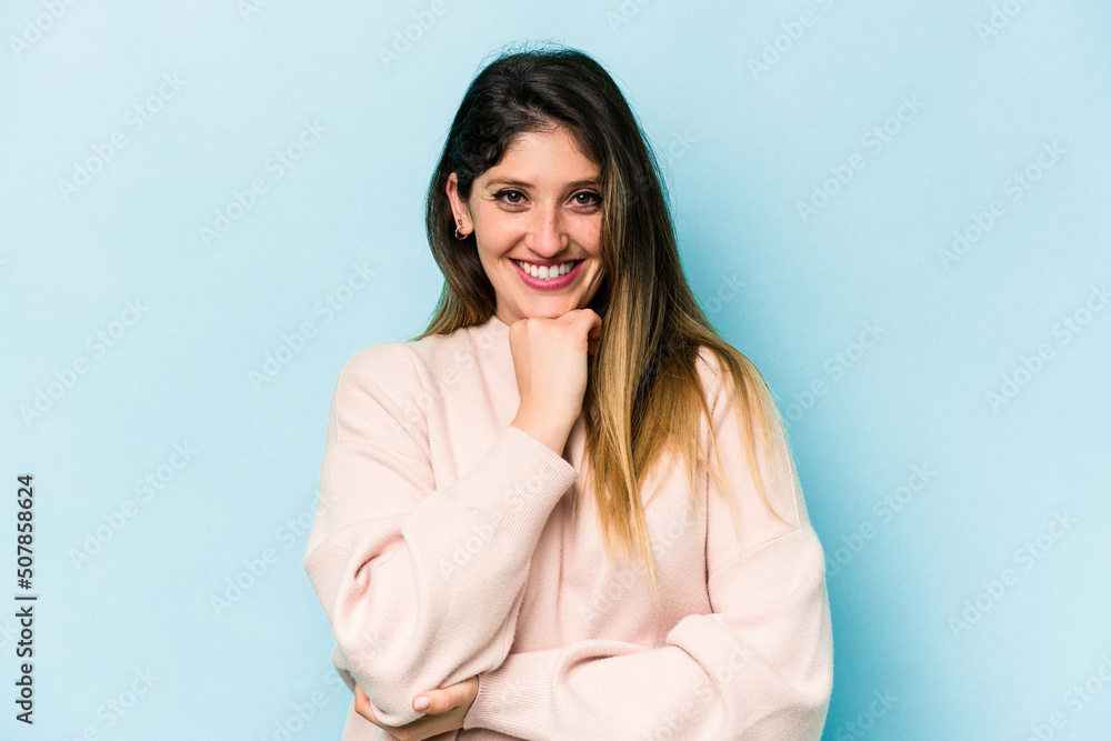 Young caucasian woman isolated on blue background smiling happy and confident, touching chin with hand.