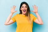 Young caucasian woman isolated on blue background receiving a pleasant surprise, excited and raising hands.