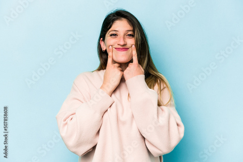 Young caucasian woman isolated on blue background doubting between two options. © Asier